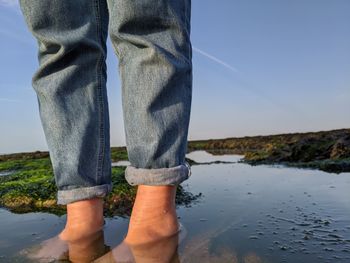 Low section of man standing on beach