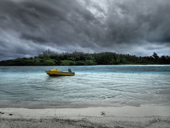 Boats in sea against cloudy sky