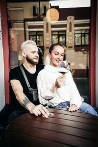 Young couple holding wineglass while sitting at cafe