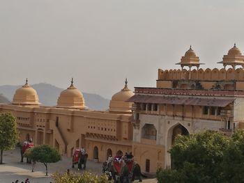 People outside temple against clear sky