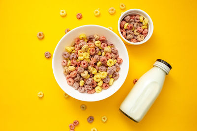 Healthy breakfast concept, colorful ring cereals in large bowl and mini bowl with milk in bottle.
