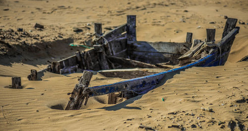 Abandoned boat buried in sand at beach