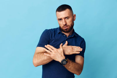 Portrait of young man standing against blue background