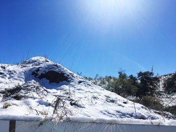 Scenic view of snow covered mountains against clear blue sky