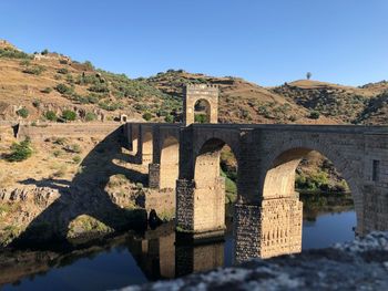 Arch bridge over river against blue sky