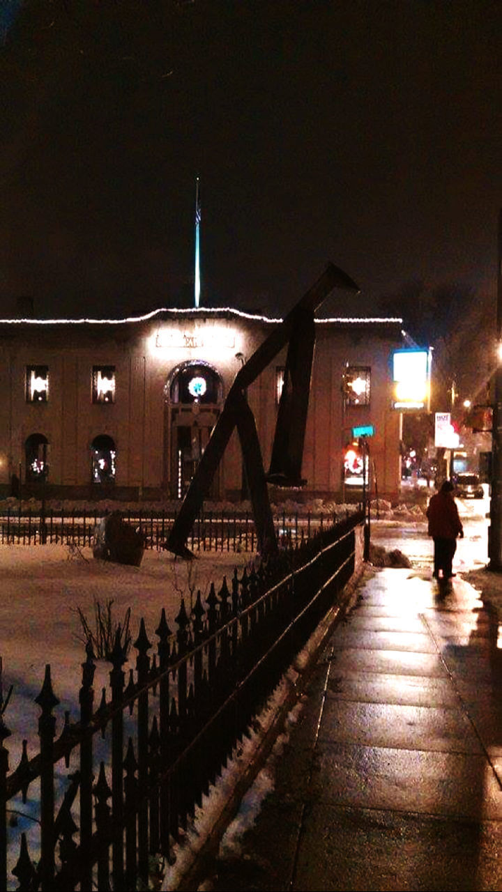 REAR VIEW OF PEOPLE WALKING ON ILLUMINATED BRIDGE AT NIGHT