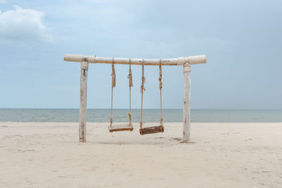 Wooden posts on beach against sky