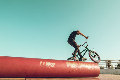 Man with bicycle against clear blue sky