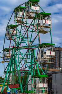 Low angle view of ferris wheel against buildings in city