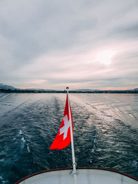 Swiss flag on a lake against sky