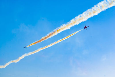 Low angle view of airplane flying against blue sky