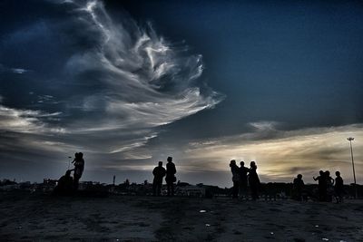 Silhouette people at beach against sky during sunset