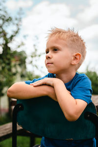 Portrait of a little serious boy in a blue t-shirt outdoors.