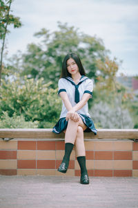 Portrait of a smiling young woman sitting against trees
