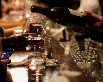 Cropped image of bartender pouring wine in glass at bar