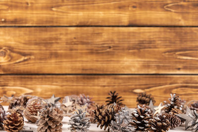 Close-up of pine cones on table against wooden wall