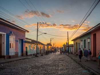 Cobbled street amidst houses against sky during sunset