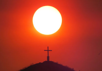 Silhouette cross against sky during sunset