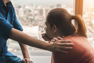 Midsection of woman with hands sitting on window