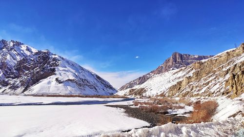Scenic view of snowcapped mountains against blue sky