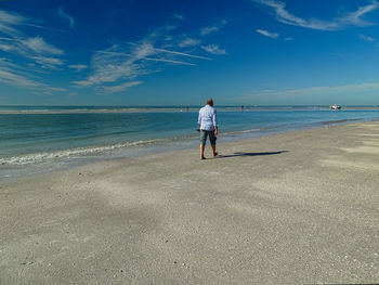 Rear view of woman on beach against sky