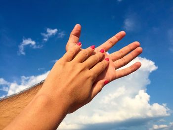 Close-up of hands against blue sky