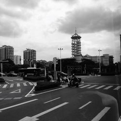 View of city street against cloudy sky