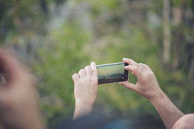 Man photographing with mobile phone outdoors