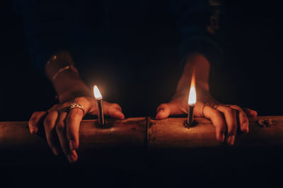 Close-up of hands burning candles