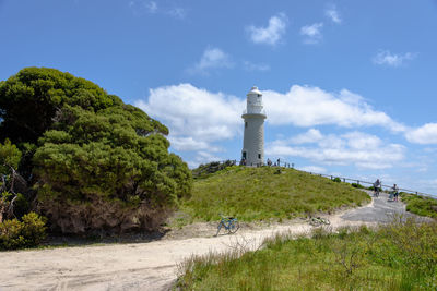 Lighthouse amidst trees and buildings against sky