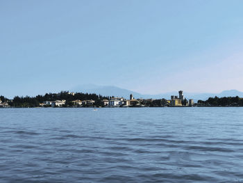 Sea by buildings against clear sky