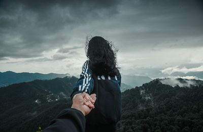 Midsection of woman against mountain range against sky