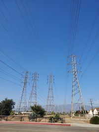 Low angle view of electricity pylon against blue sky