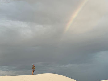 Rear view of man standing on mountain against sky