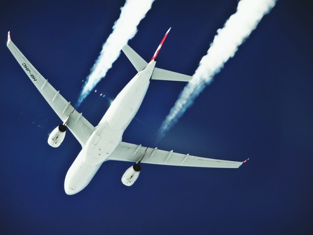 airplane, flying, air vehicle, transportation, mode of transport, aircraft wing, low angle view, blue, mid-air, travel, sky, journey, part of, outdoors, flag, day, no people, on the move, clear sky, cropped