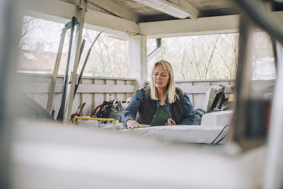 Mature woman cleaning speedboat in garage