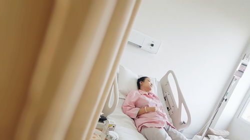 High angle view of woman lying on bed at hospital ward