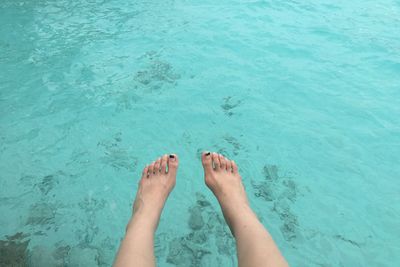 Low section of woman over turquoise sea