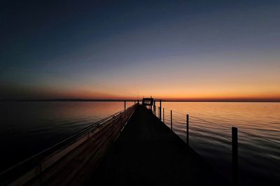 Pier over sea against sky during sunset