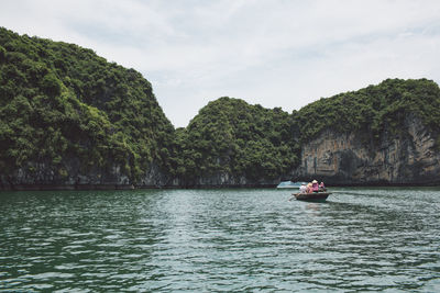 People rowing boat on halong bay against rocky mountains