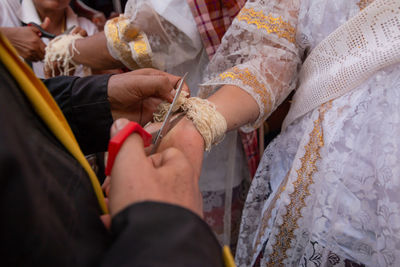 Cropped image of priest cutting brides bracelet during wedding ceremony