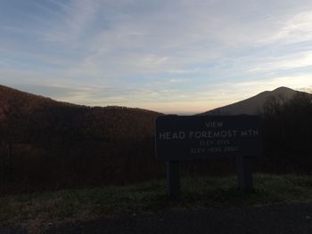 Information sign on mountain against sky