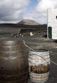 Wine casks on field against cloudy sky