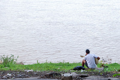 Rear view of men sitting by lake