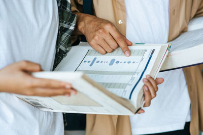 Midsection of students reading book