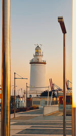 Lighthouse by sea against clear sky