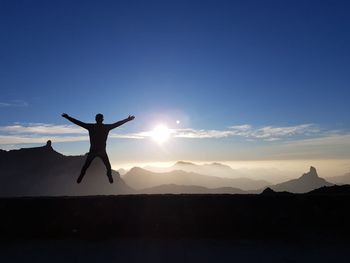 Silhouette man jumping against sky during sunset