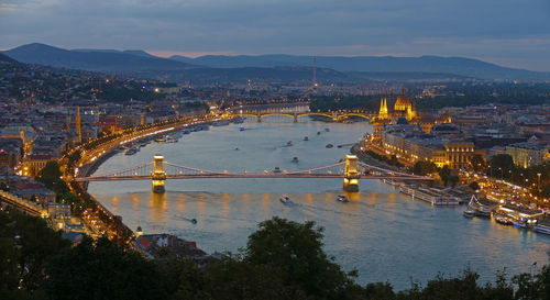 Illuminated bridge over river in city