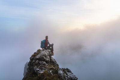 Man standing on rock against sky