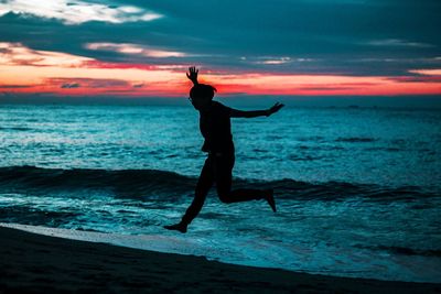 Silhouette man on beach against sky during sunset